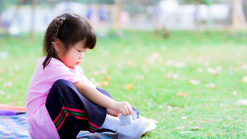 young child putting on shoes to do exercise